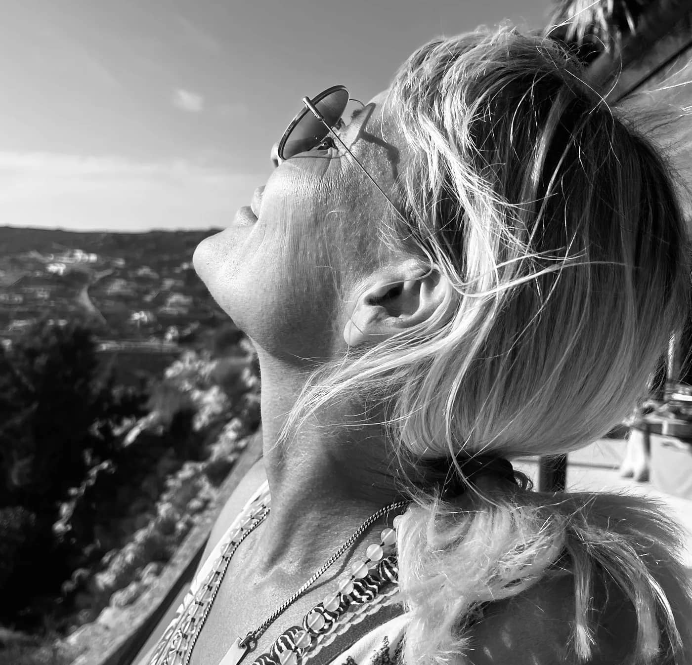 Tina Maria Werner mit Sonnenbrille hebt das Gesicht der Sonne entgegen, schwarz-weiß