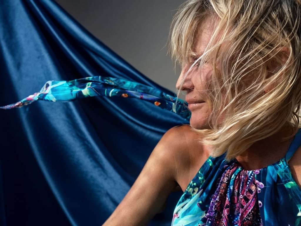 Tina Maria Werner, das Haar im Wind, vor königsblauem Stoff